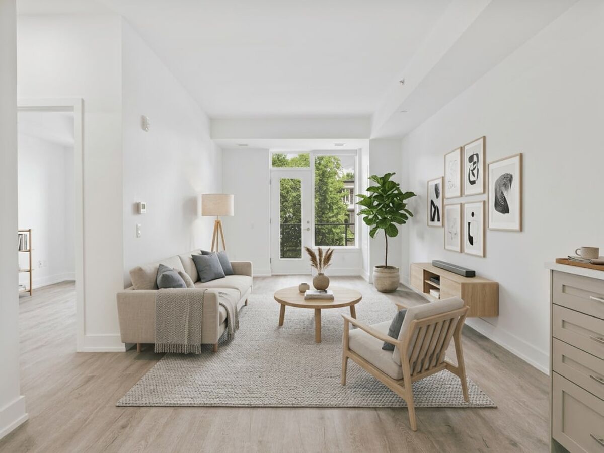 Before: a bright living room with white walls, a beige sofa, a round wooden table and an armchair.